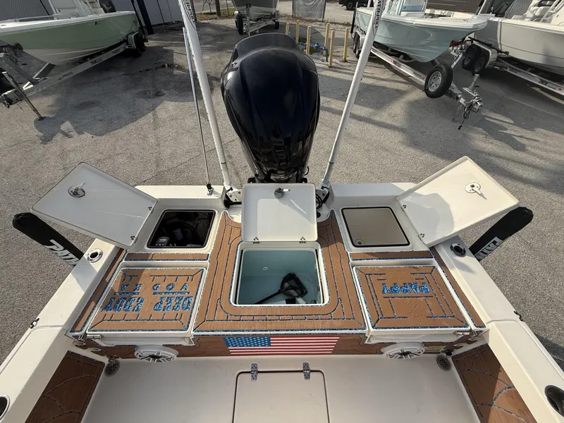Slide: The Image of 2021 Pathfinder 2400 TRS boat deck with storage compartments and motor, docked outdoors. - 14