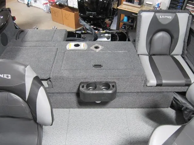 Slide: The Image of 2025 Lund 1875 Crossover XS boat interior with gray seating and storage compartments. - 10