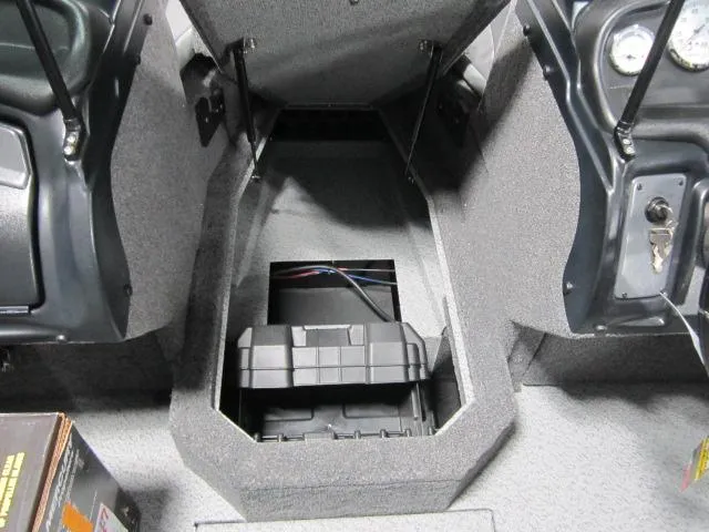 Slide: The Image of 2025 Lund 1875 Crossover XS boat interior storage compartment with open lid and visible wiring. - 7