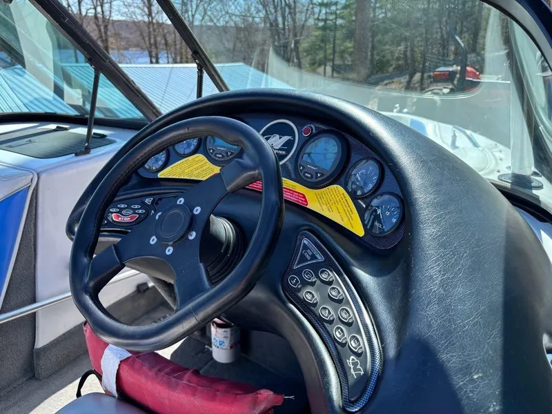 Slide: The Image of 2000 Nautique Air Nautique boat dashboard with steering wheel and control panel. - 15