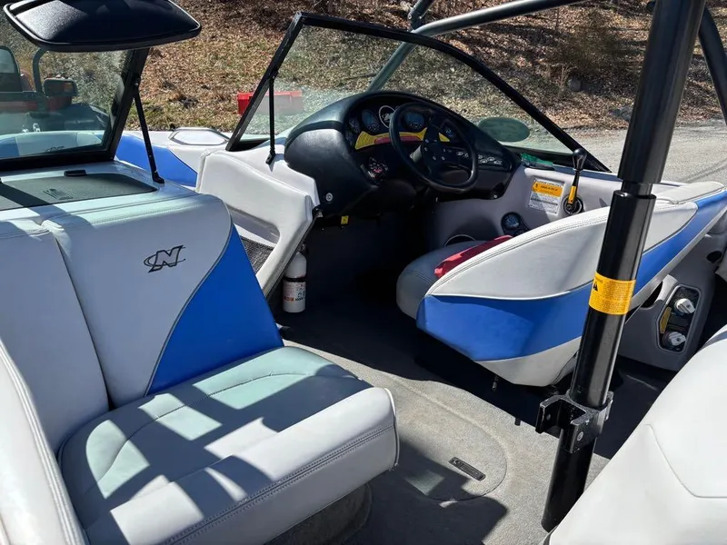 Slide: The Image of 2000 Nautique Air Nautique boat interior with blue and white seating, steering wheel, and dashboard. - 20