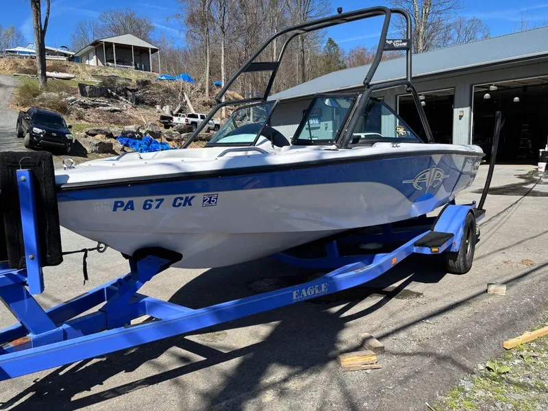 Slide: The Image of 2000 Nautique Air Nautique boat on blue trailer, parked outdoors near a garage. - 5