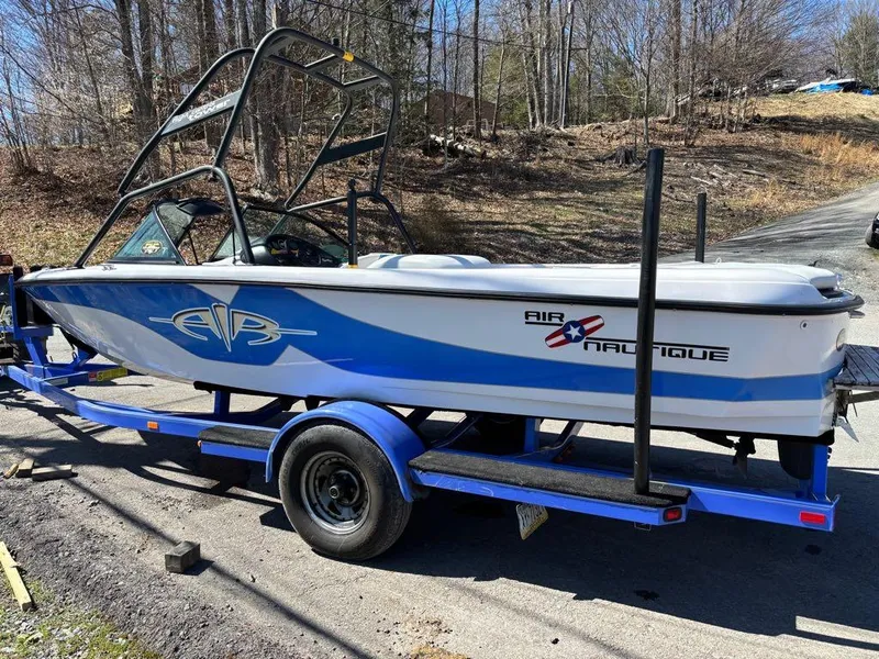 Slide: The Image of 2000 Nautique Air Nautique boat on trailer, parked outdoors in a wooded area. - 7