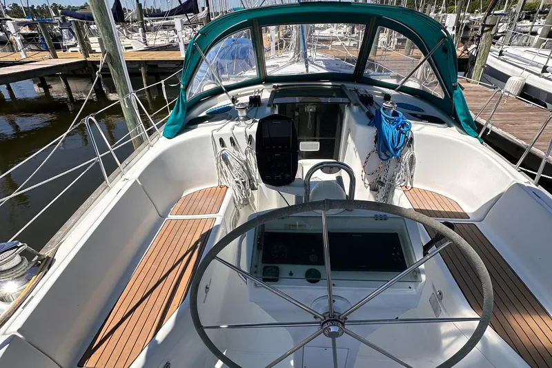 Slide: The Image of 2000 Beneteau 411 sailboat cockpit with steering wheel, wood accents, and marina background. - 11