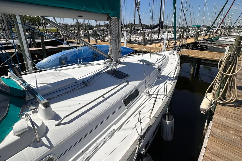 Slide: The Image of 2000 Beneteau 411 sailboat docked at marina, featuring white deck and teal accents. - 12