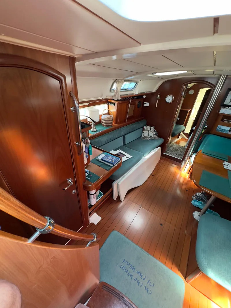 Slide: The Image of Interior of a 2000 Beneteau 411 sailboat with wooden finishes and teal seating. - 19