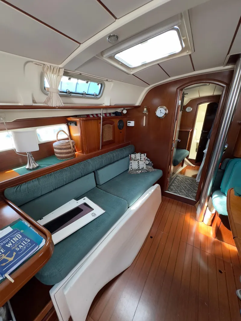 Slide: The Image of Interior of 2000 Beneteau 411 sailboat with wooden flooring and cozy seating area. - 20