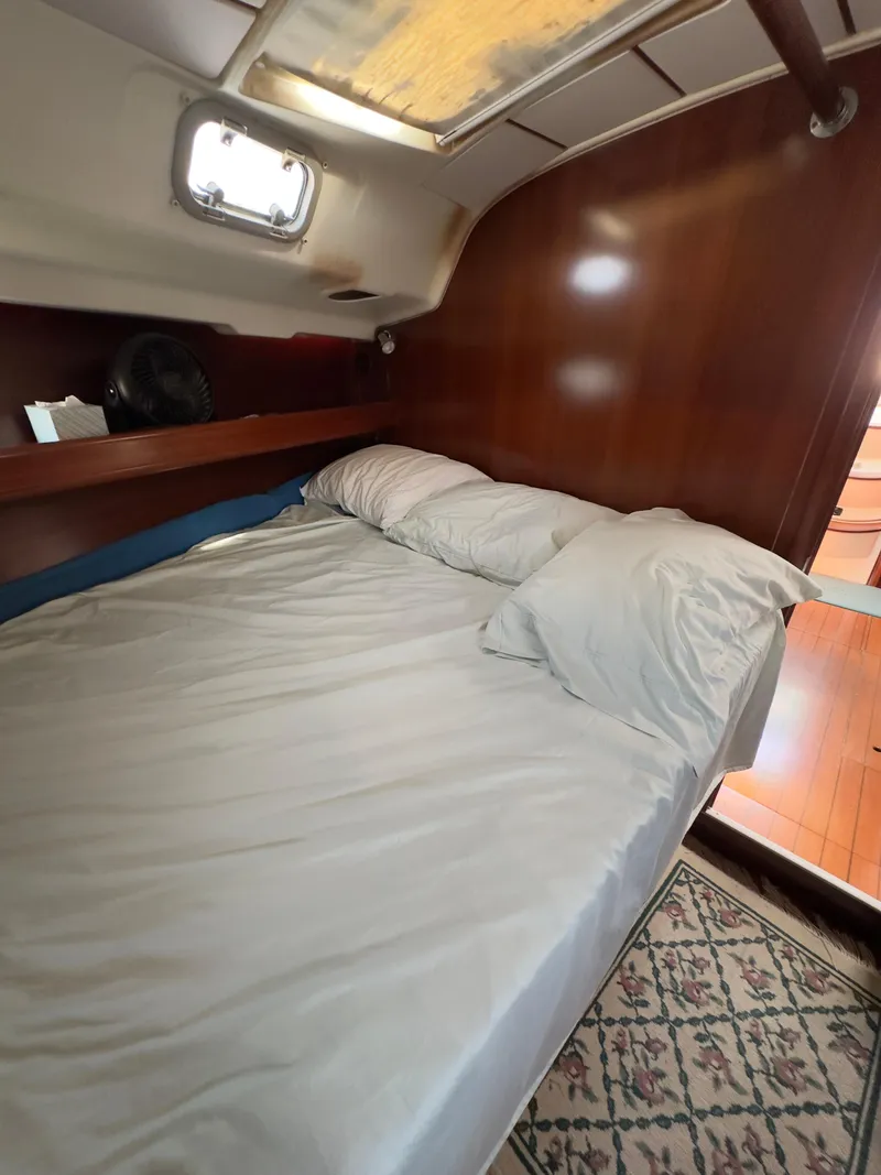 Slide: The Image of Cozy cabin interior of a 2000 Beneteau 411 sailboat with a neatly made bed. - 22