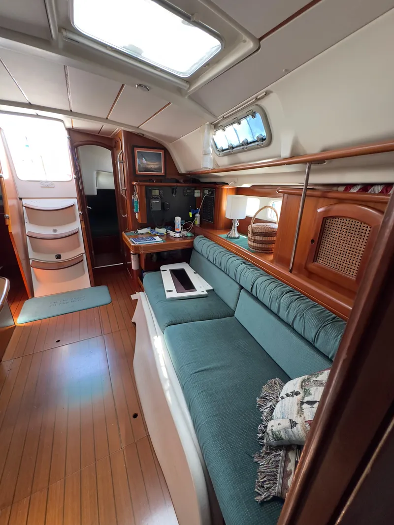Slide: The Image of Interior of 2000 Beneteau 411 sailboat with teal seating and wooden accents. - 23