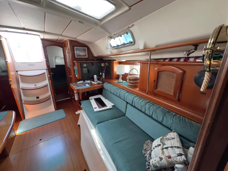 Slide: The Image of Interior of 2000 Beneteau 411 sailboat with teal seating and wooden accents. - 24