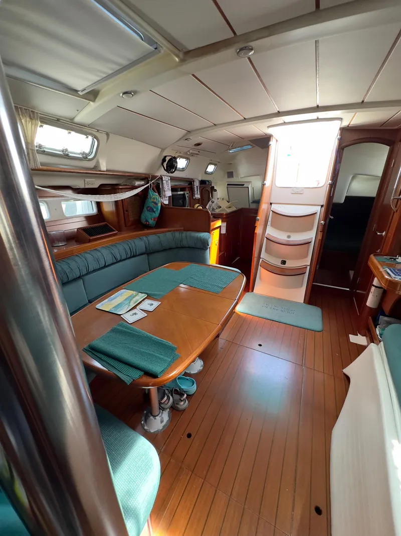 Slide: The Image of Interior of 2000 Beneteau 411 sailboat with wooden flooring and cozy seating area. - 25