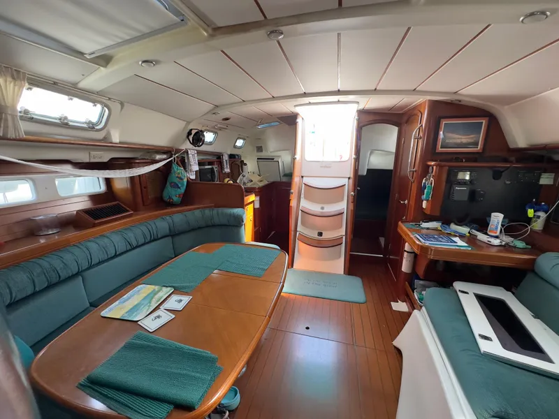 Slide: The Image of Interior of a 2000 Beneteau 411 sailboat, featuring a cozy dining area and navigation station. - 26