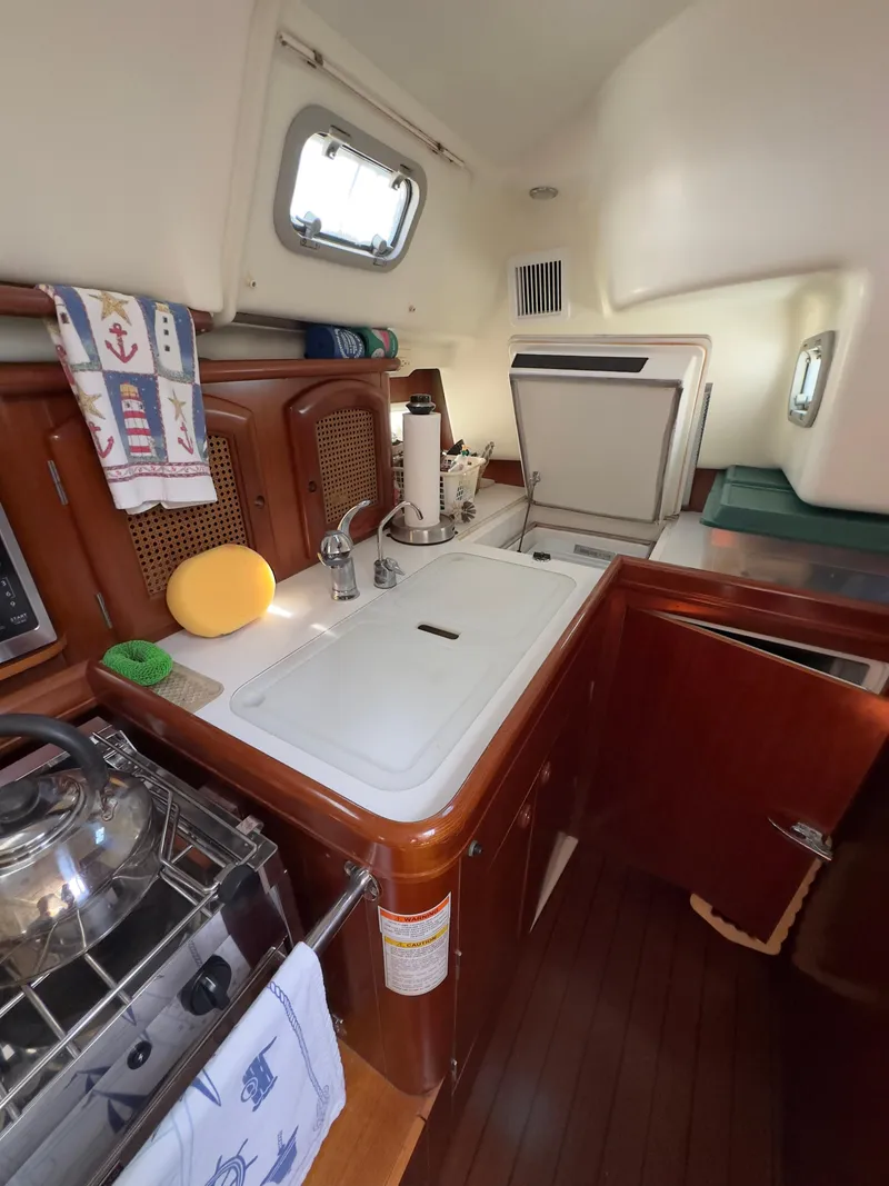Slide: The Image of Interior of 2000 Beneteau 411 sailboat kitchen with sink, stove, and storage. - 28
