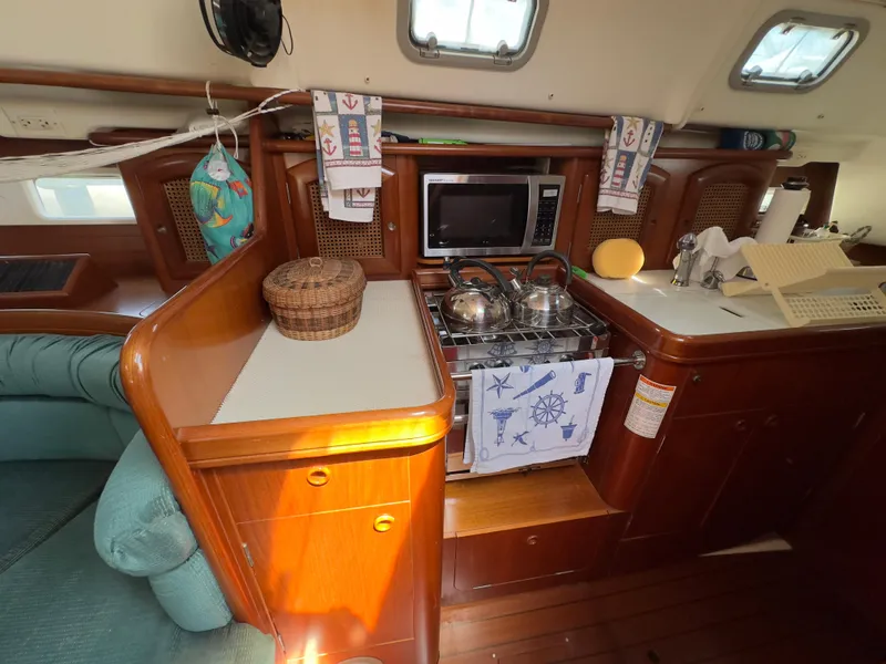 Slide: The Image of Cozy kitchen area in a 2000 Beneteau 411 sailboat with wooden cabinetry and appliances. - 29
