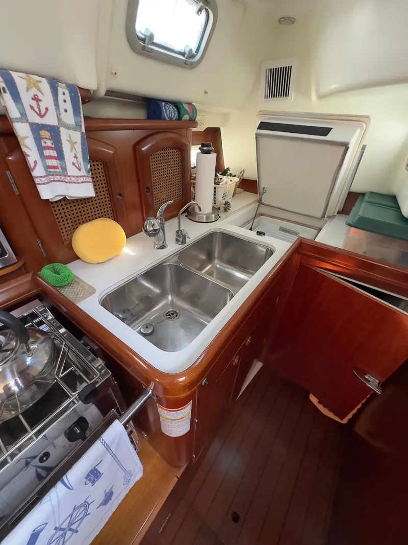 Slide: The Image of Beneteau 411 yacht kitchen with double sink, wooden cabinetry, and compact appliances, year 2000 model. - 32