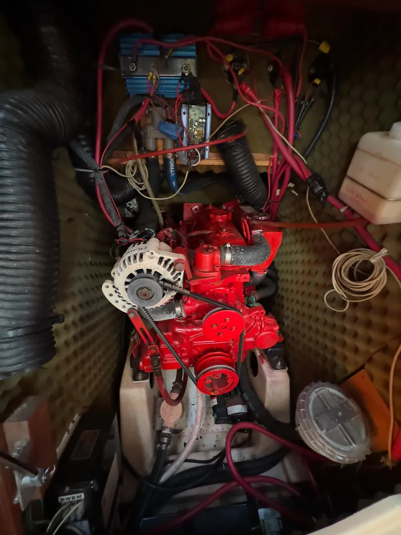 Slide: The Image of Engine compartment of a 2000 Beneteau 411 sailboat, featuring a red engine and wiring. - 41