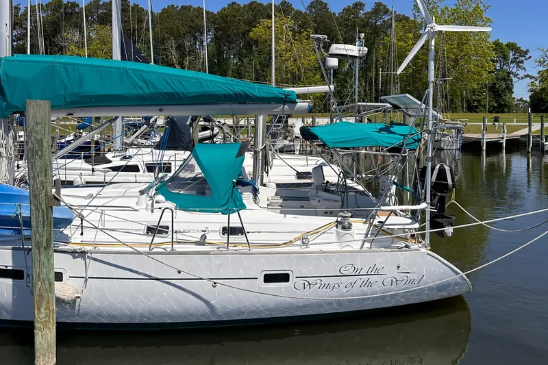 Slide: The Image of Beneteau 411 sailboat from 2000 docked, featuring teal covers and wind turbine. - 8