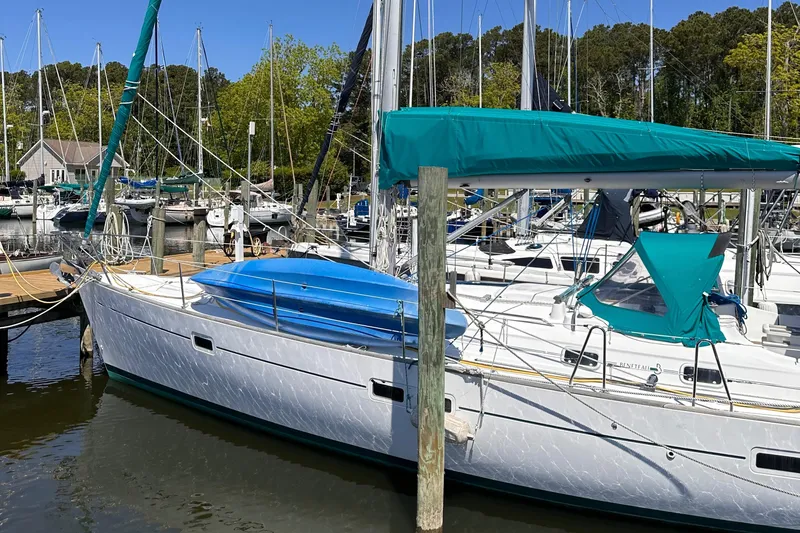 Slide: The Image of 2000 Beneteau 411 sailboat docked in a marina, featuring teal covers and a sleek design. - 9