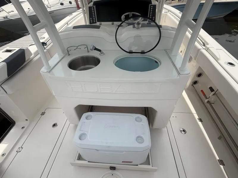 Slide: The Image of 2019 Robalo R302 Center Console boat interior with steering wheel, sink, and cooler. - 24