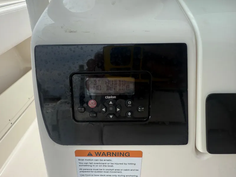 Slide: The Image of 2019 Robalo R302 Center Console boat dashboard with Clarion audio system and warning label. - 46