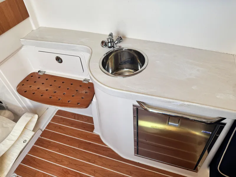 Slide: The Image of 2017 Grady-White Canyon 376 boat interior with sink, wooden seat, and stainless steel fridge. - 13