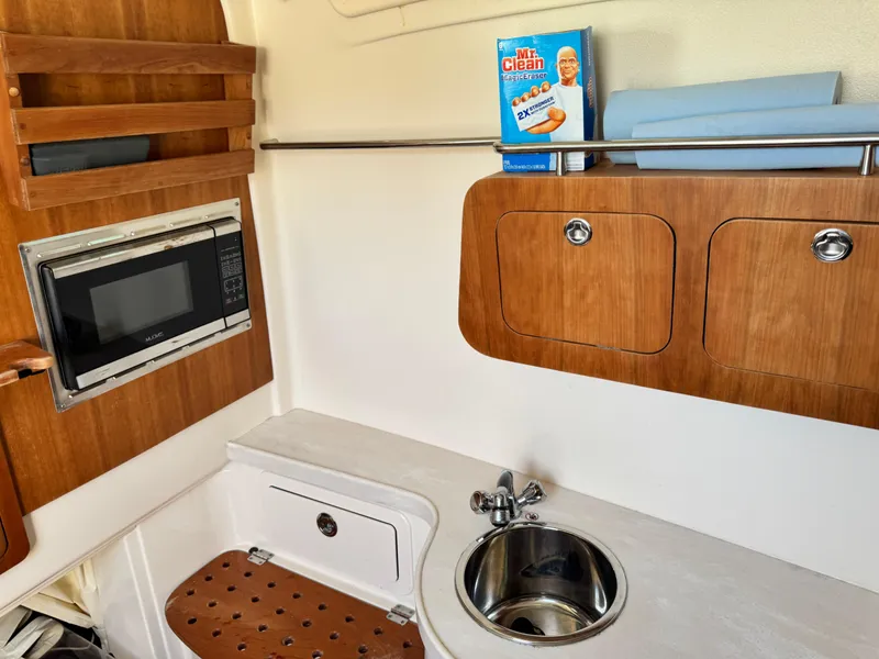 Slide: The Image of 2017 Grady-White Canyon 376 interior with sink, microwave, and wooden cabinets. - 14