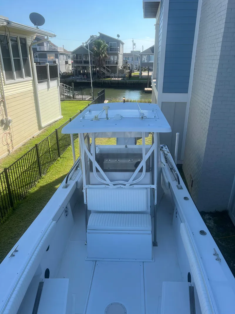 Slide: The Image of 1993 KenCraft Challenger 250CC boat docked between houses, featuring a spacious deck and T-top. - 17