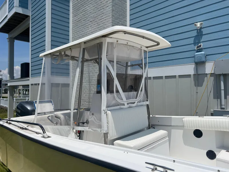 Slide: The Image of 1993 KenCraft Challenger 250CC boat with white seating and canopy, docked near a blue building. - 9