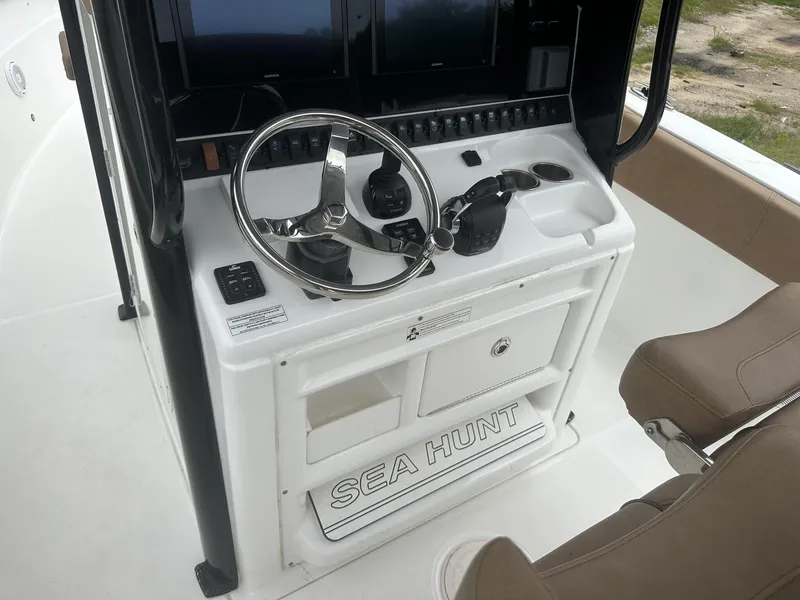 Slide: The Image of 2020 Sea Hunt Gamefish 30 helm with steering wheel and controls, featuring a coffin box. - 29