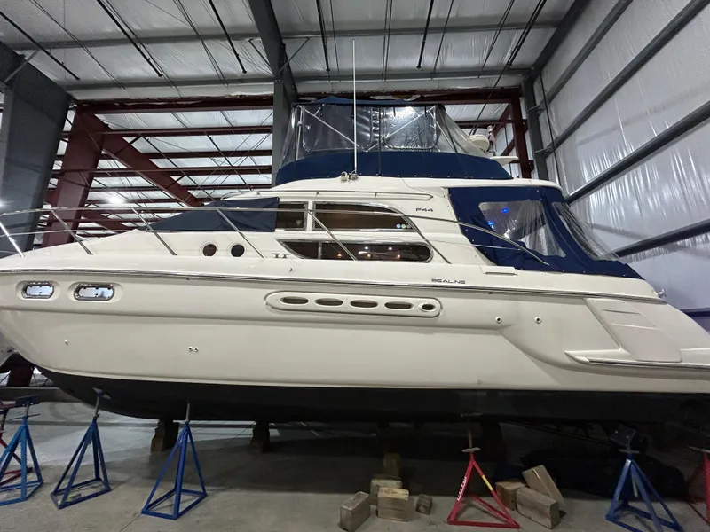 Slide: The Image of 2000 Sealine F44 yacht in storage, elevated on stands in a metal warehouse. - 4