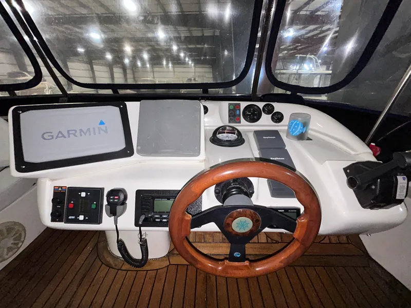 Slide: The Image of Sealine F44 2000 yacht helm with Garmin navigation, wooden steering wheel, and control panel. - 47