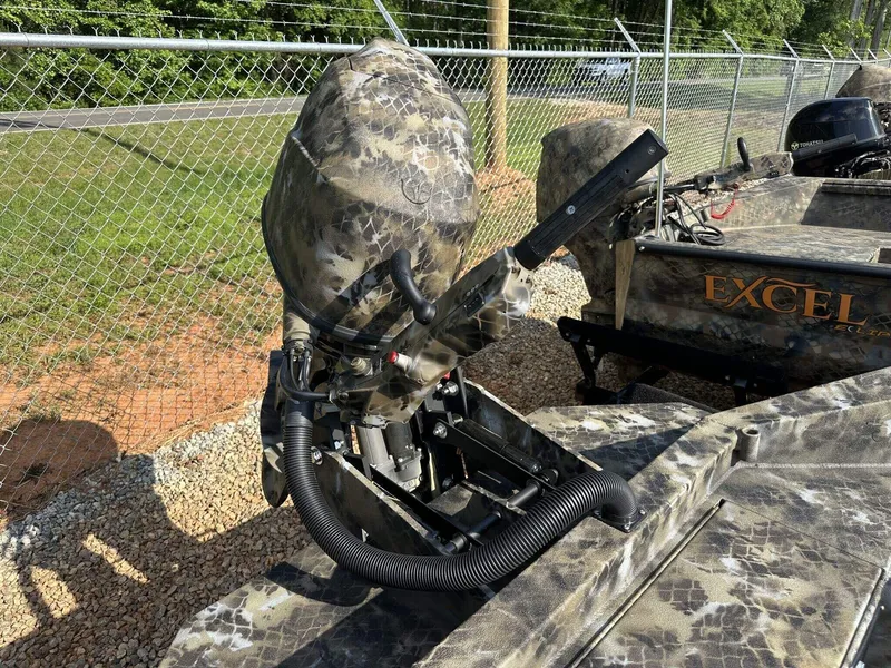 Slide: The Image of 2025 Excel Viper F4 1751 boat with camo design and outboard motor, parked outdoors. - 6