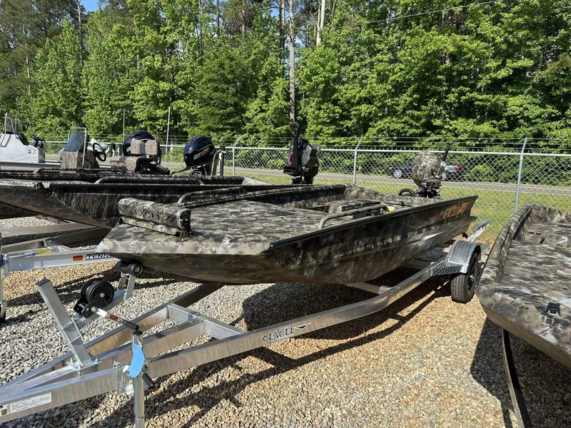 Slide: The Image of 2025 Excel Viper F4 1751 boat with camouflage design on a trailer, surrounded by trees. - 1