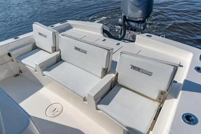 Slide: The Image of 2024 Pathfinder 2600 TRS boat interior with cushioned seating and motor on water. - 13