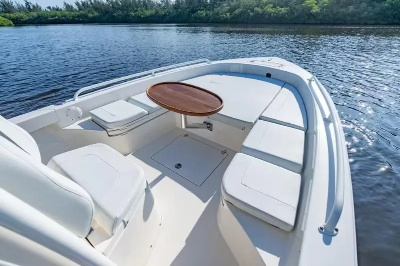 Slide: The Image of 2024 Pathfinder 2600 TRS boat interior with seating and table on calm water. - 16