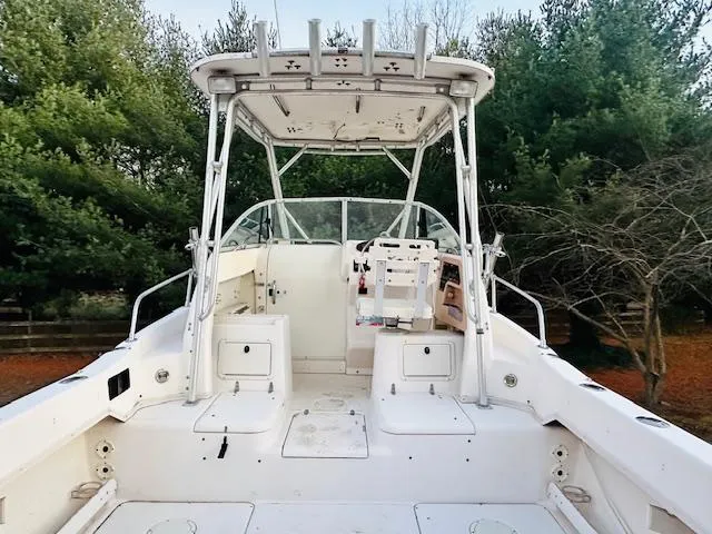 Slide: The Image of 1997 Grady-White F-26 Tigercat boat with spacious deck and canopy, surrounded by trees. - 4