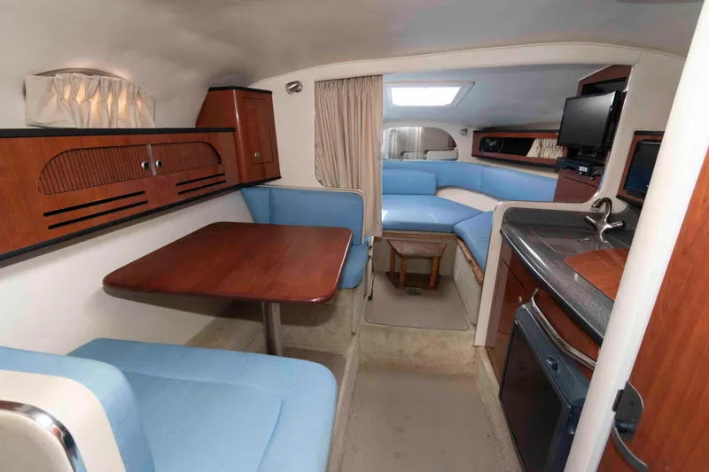 Slide: The Image of 2007 Sea Ray 280 Sundancer interior with blue seating, wooden table, and kitchenette. - 6