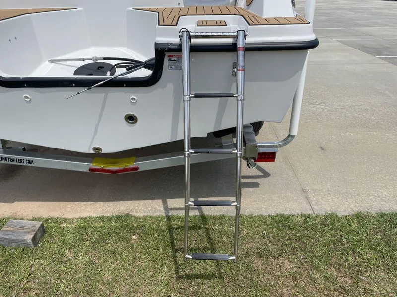 Slide: The Image of Starcraft SVX-171 boat ladder, 2025 model, on a trailer, parked on grass. - 5