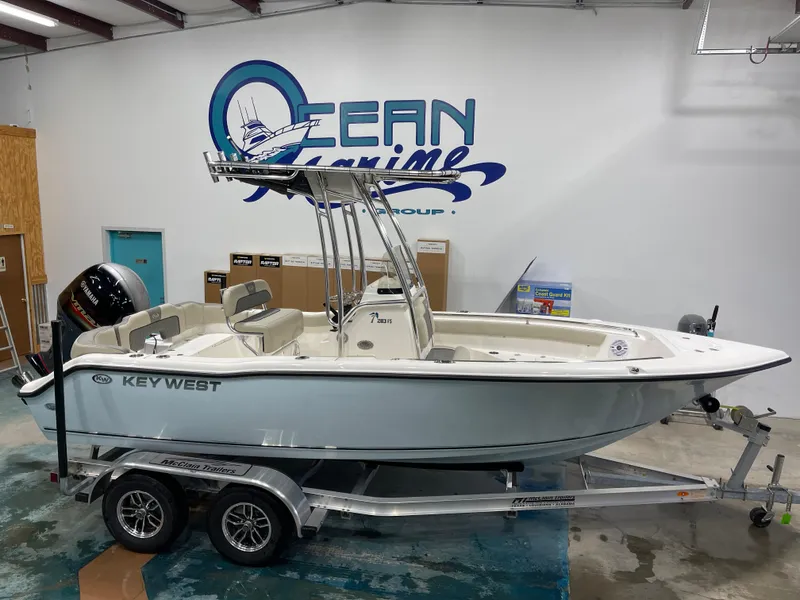 Slide: The Image of 2025 Key West 203FS boat on trailer in showroom, Ocean Marine Group logo in background. - 1