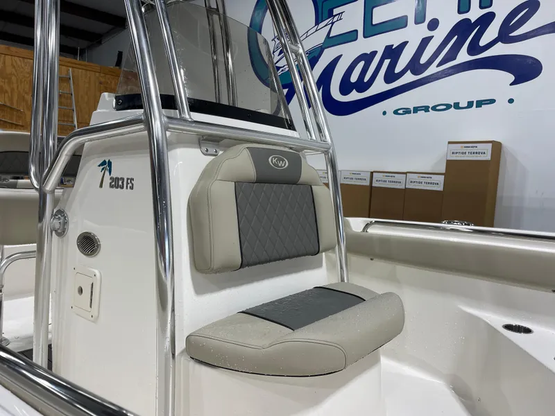 Slide: The Image of 2025 Key West 203FS boat interior with cushioned seating and sleek design in a showroom. - 14