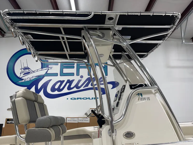 Slide: The Image of 2025 Key West 219fs boat with T-top and seating, displayed indoors at a marine showroom. - 12