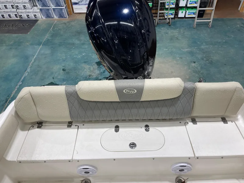 Slide: The Image of 2025 Key West 219fs boat interior with cushioned seating and motor, in showroom setting. - 19