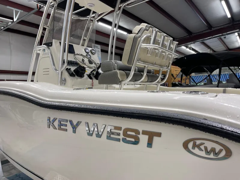 Slide: The Image of 2025 Key West 219fs boat interior with steering console and seating in a showroom. - 5