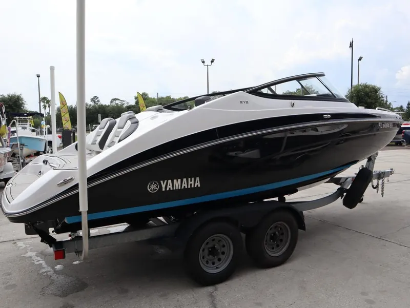 Slide: The Image of 2021 Yamaha Boats 212 on trailer, sleek black and white design, parked outdoors. - 5