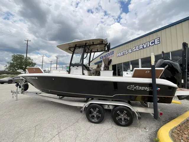 Slide: The Image of 2020 Crevalle 260HCO boat on trailer outside service center under cloudy sky. - 3