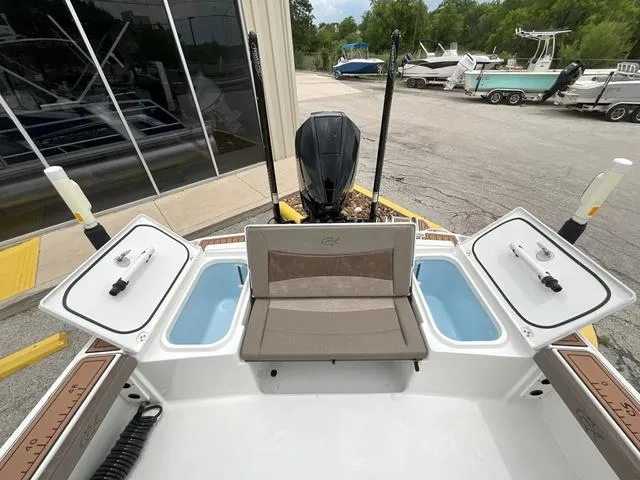Slide: The Image of 2020 Crevalle 260HCO boat with open storage compartments and seating, parked outdoors. - 6