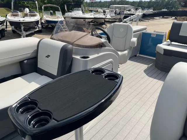Slide: The Image of 2025 Starcraft EX20QDH pontoon boat interior with seating and table, docked among other boats. - 18
