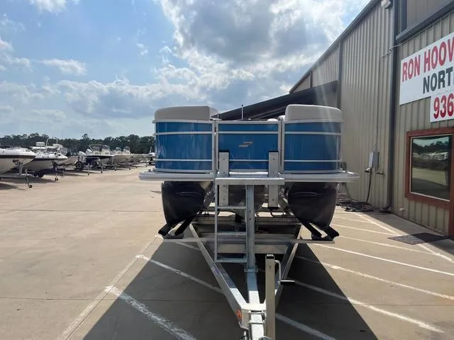 Slide: The Image of 2025 Starcraft EX20QDH pontoon boat on trailer, parked outside dealership under cloudy sky. - 3