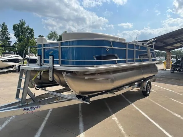 Slide: The Image of 2025 Starcraft EX20QDH pontoon boat on trailer, parked outdoors under a partly cloudy sky. - 4