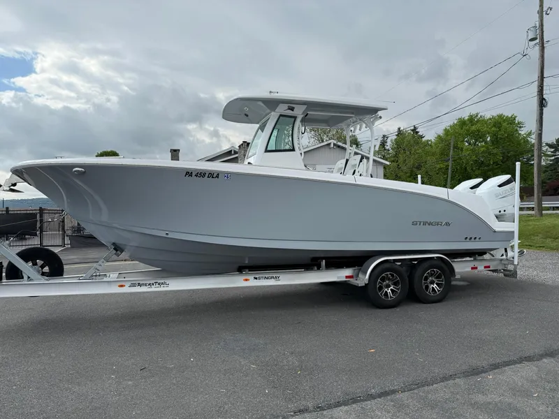 Slide: The Image of 2025 Stingray 273 CC boat on trailer, parked outdoors under cloudy sky. - 1